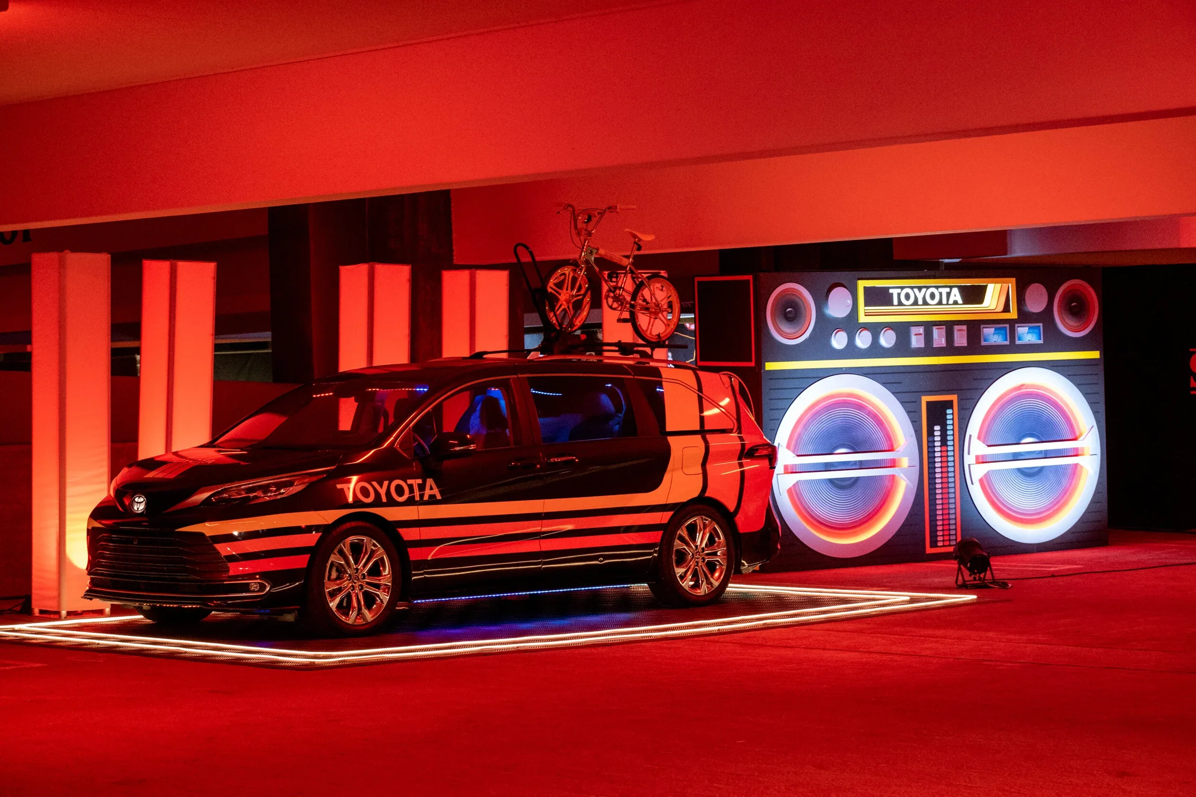 Toyota Sienna staged in a red-lit room beside an oversized boombox build